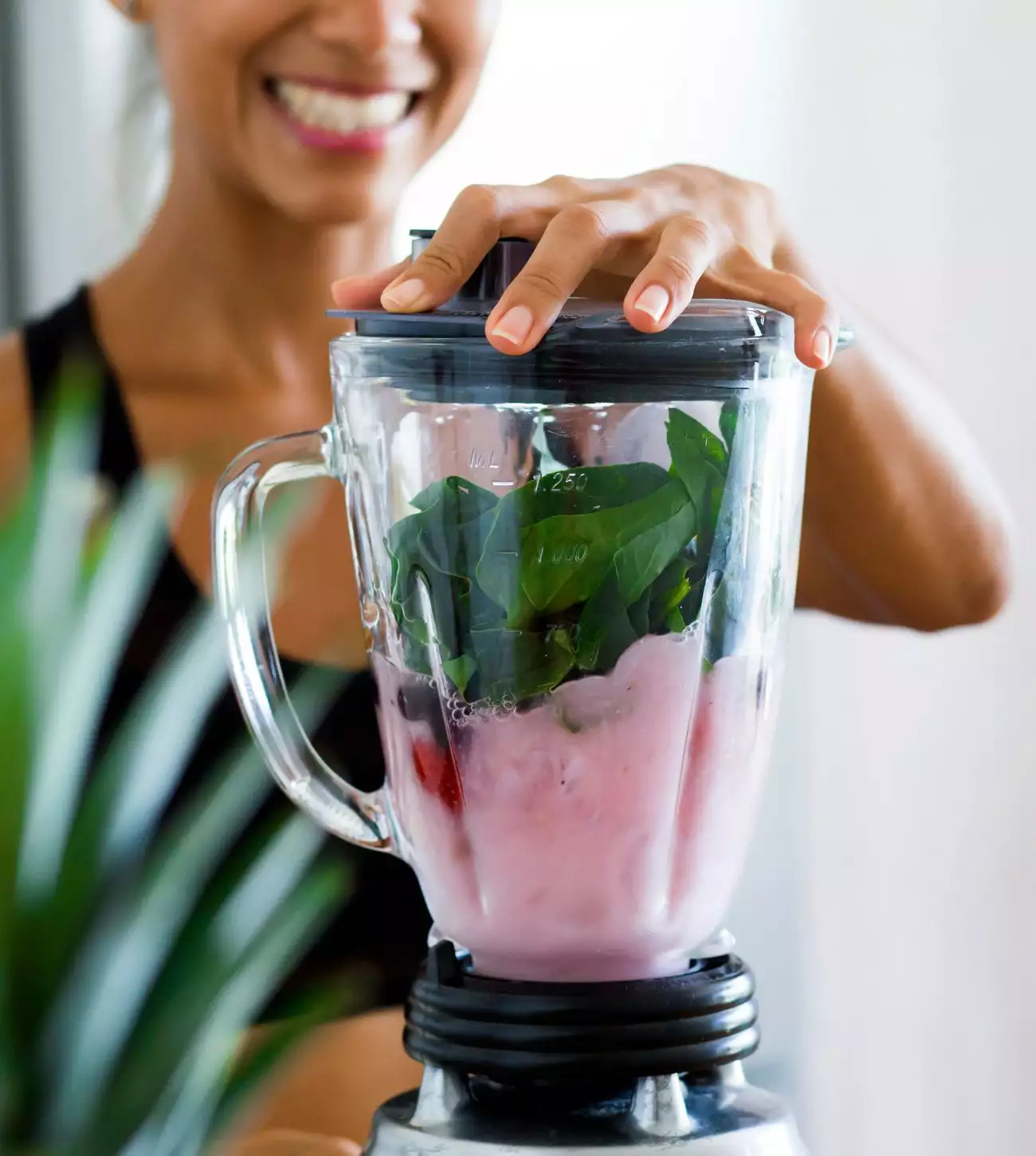 Woman preparing a fruit and spinach smoothie in the blender