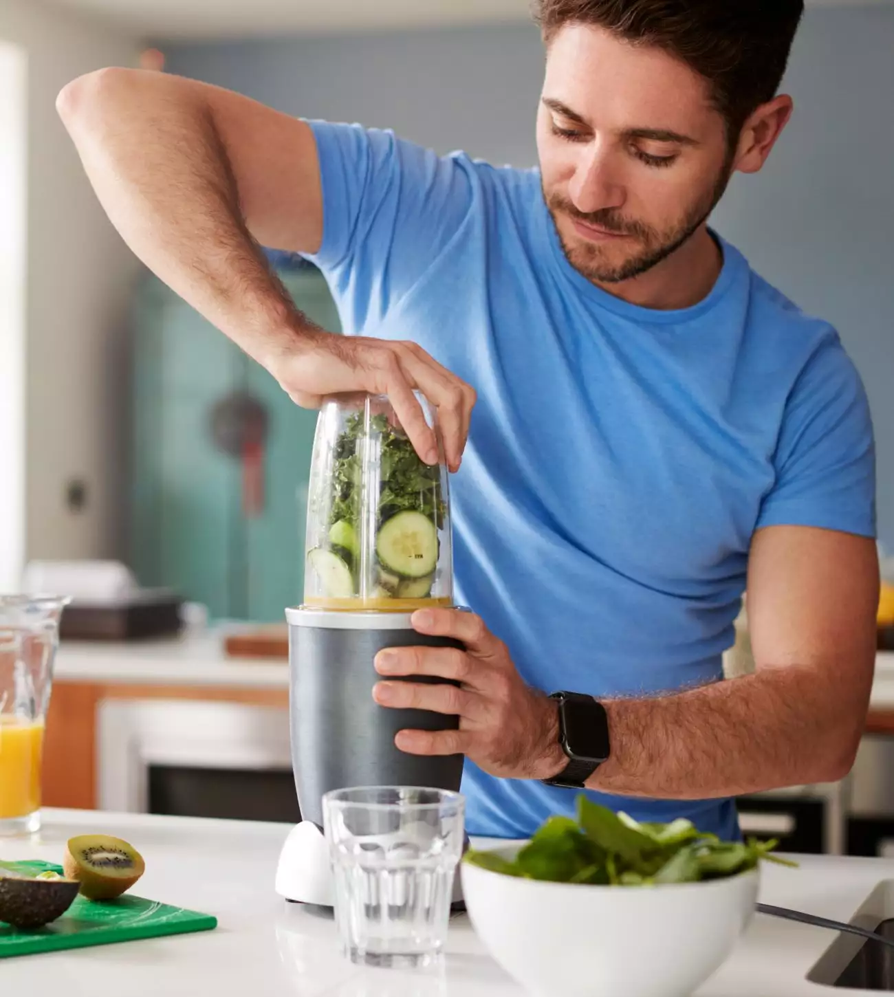 Man making a green smoothie with kale and cucumber