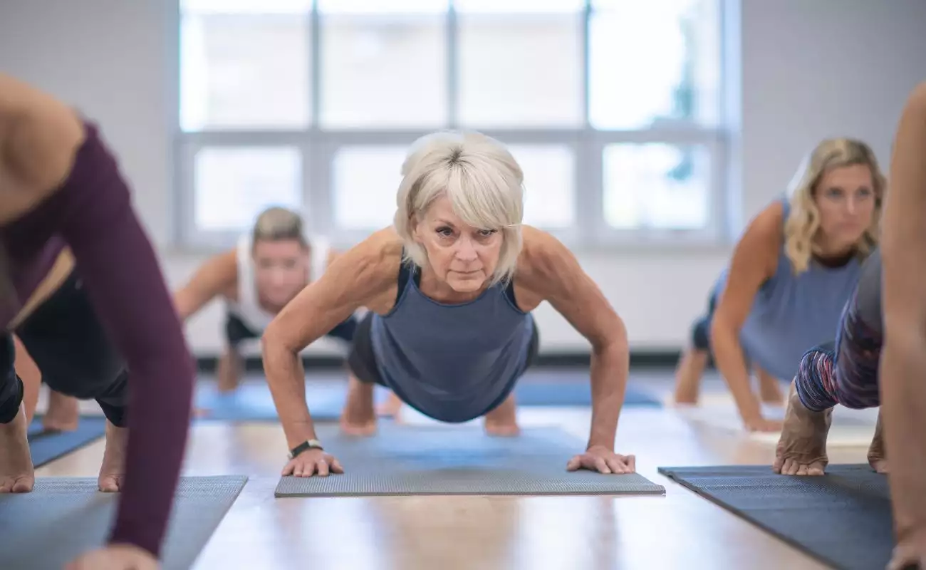 Photo focused on a mature woman in a yoga class where the class is in the middle of holding the plank position.