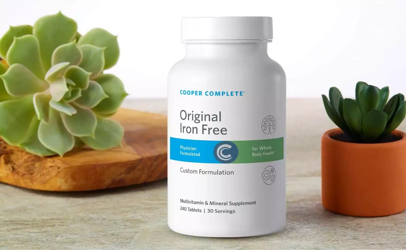 Cooper Complete Original Iron Free multivitamin and mineral formulation bottle with succulents on a counter. Bottle of comprehensive multivitamin Cooper Complete Original Iron free for adults, multivitamin for men, multivitamin for women 