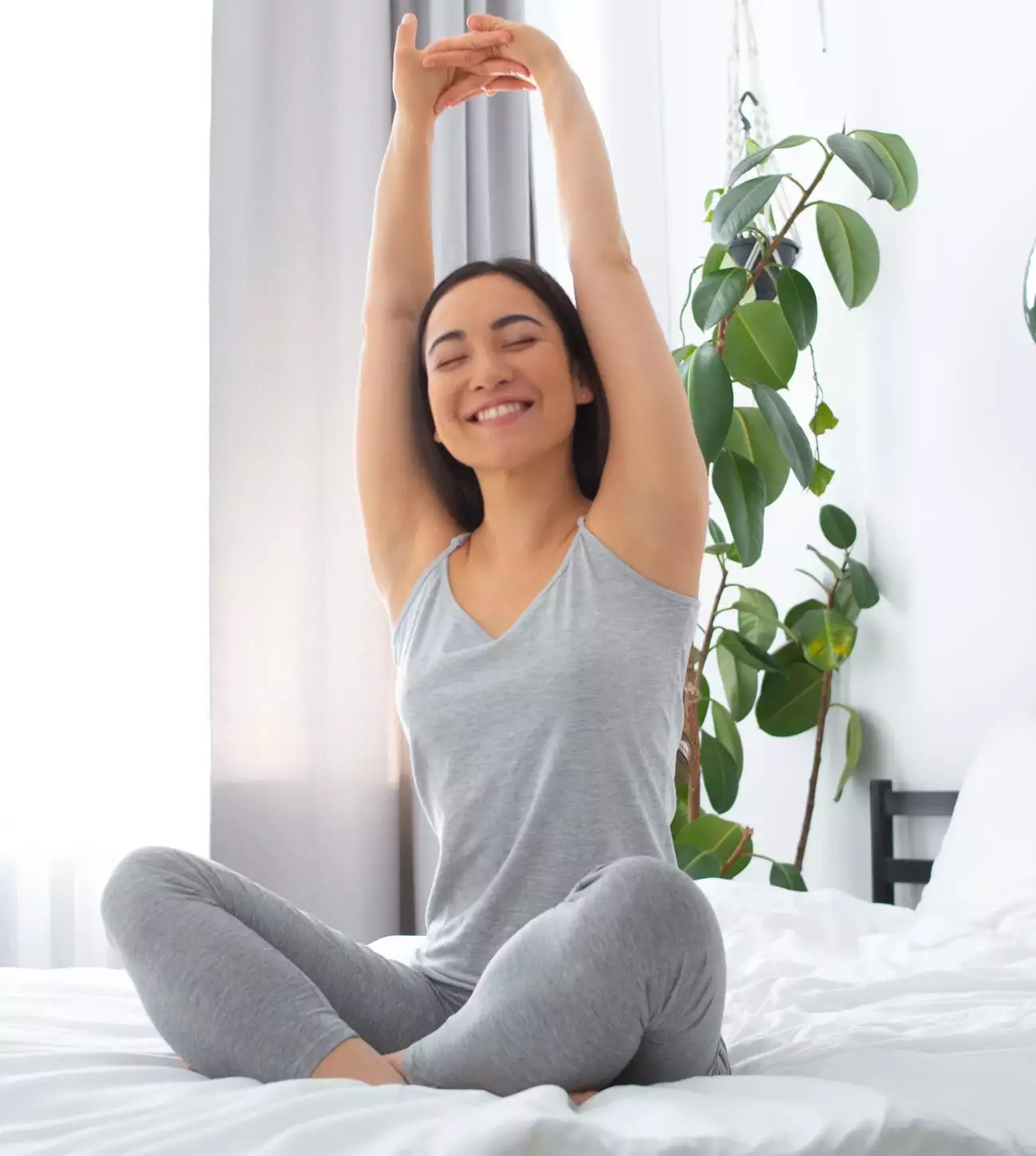 Photo of a young woman stretching on her bed.